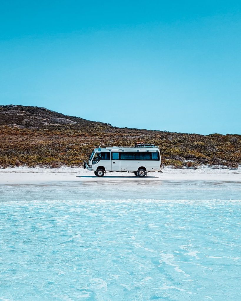 Bus on the sand on the beach on a sunny day and turquoise waters in Lucky Bay, Esperance, Western Australia