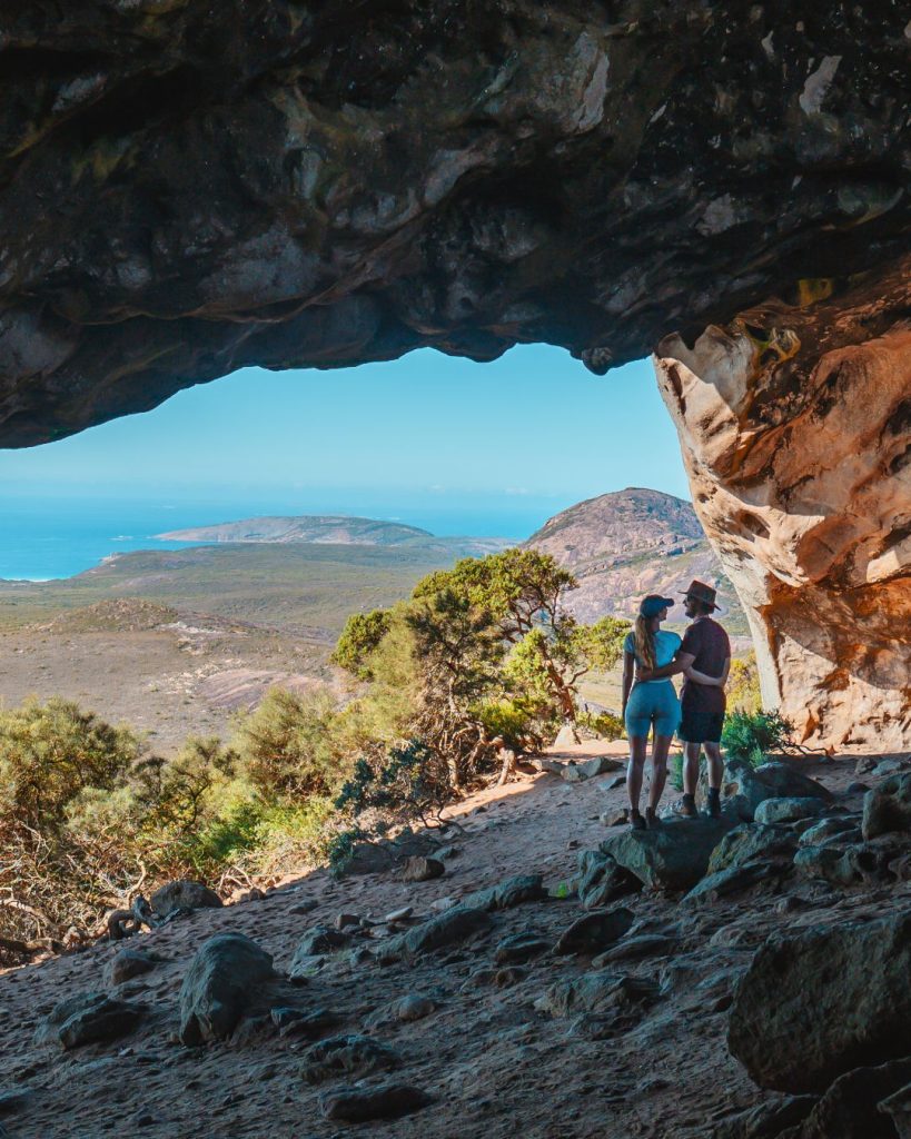 Couple standing inside a cave with views of the mountains and the sea, in Frenchmans Peak, Esperance, WA