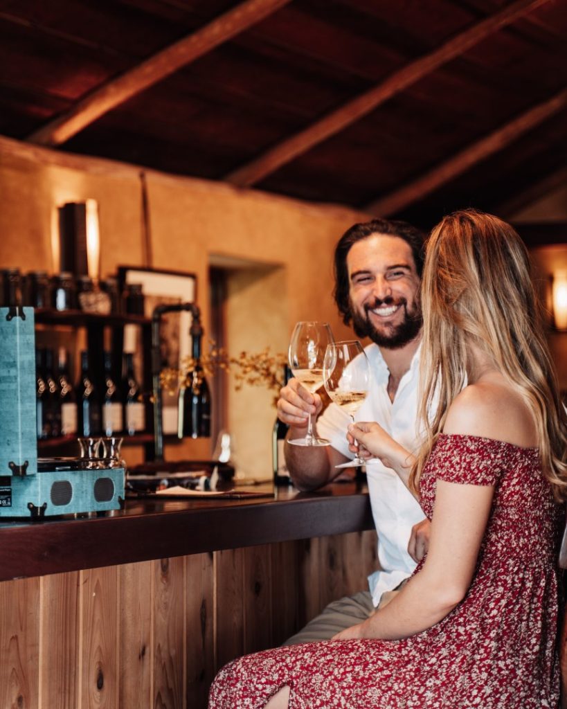 A smiling couple clinking wine glasses inside a cozy winery in Margaret River.