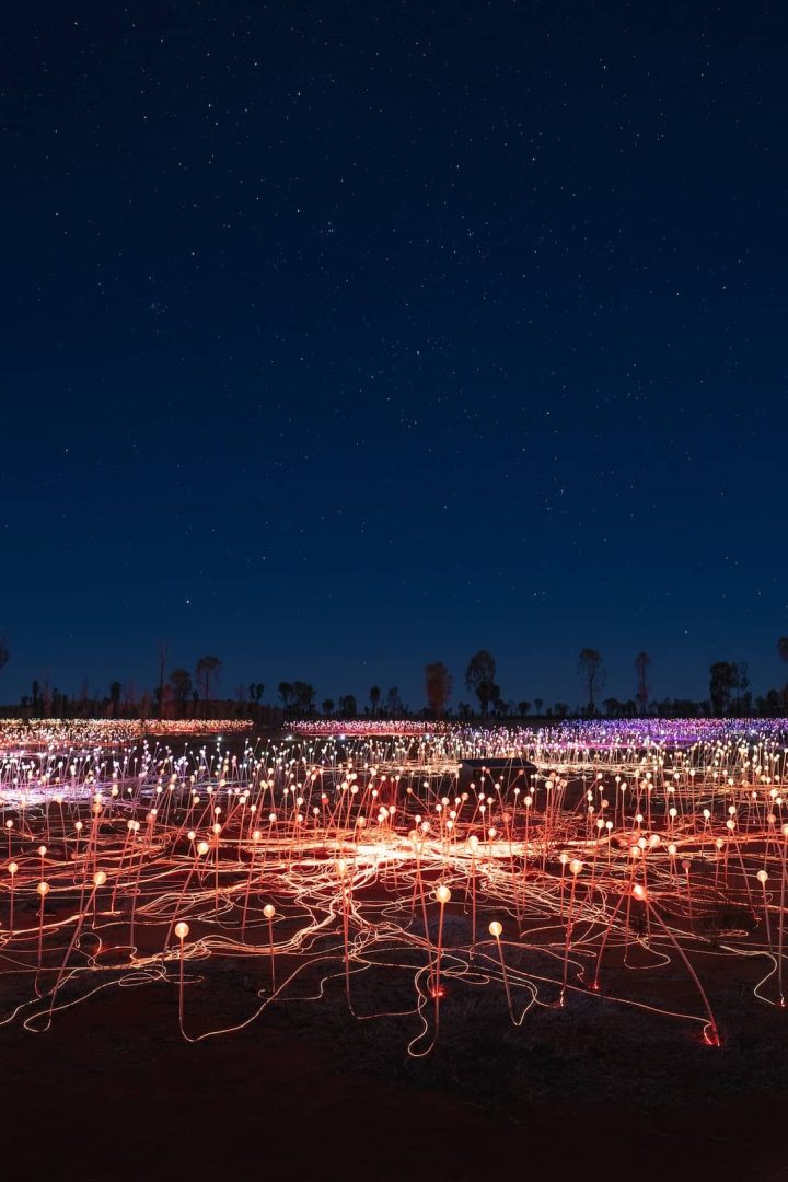 Bruce Munro’s Field of Light installation glows under a starry night sky near Uluru, a popular stop on the red centre way. Thousands of coloured lights spread across the desert floor in vibrant patterns.