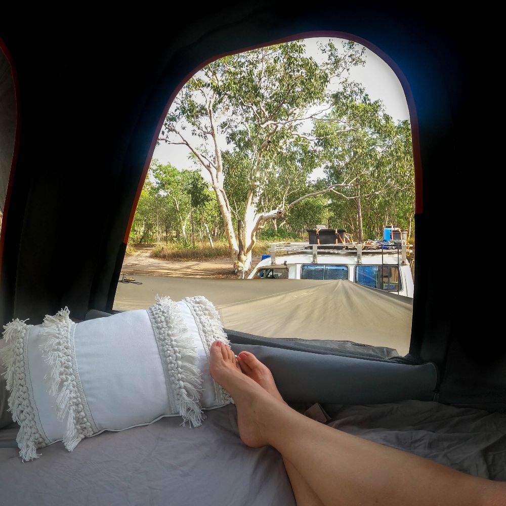 Woman's feet looking out a campsite while in tent. One of the 13 unmissable activities in Kakadu National Park.