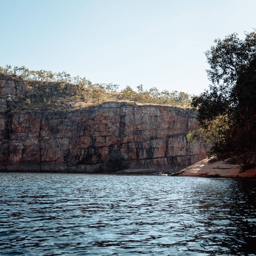 A large body of water surrounded by trees and rock. One of the things while hiking some of the very best trails of NT. This site is along the Jatbula Trail in Nitmiluk, Alice Springs.