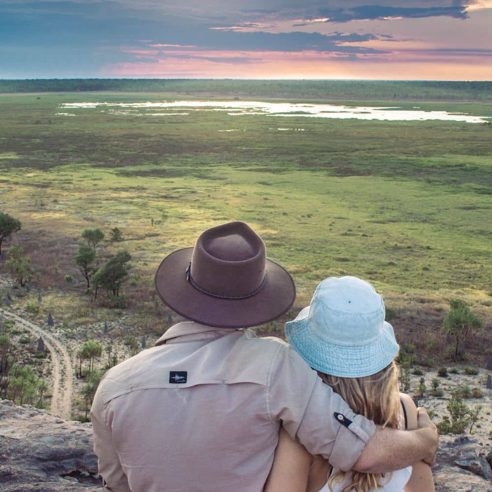 A man and woman holding one another while looking at the sunset at Ubirr rock. One of the best things to do in Kakadu national park.