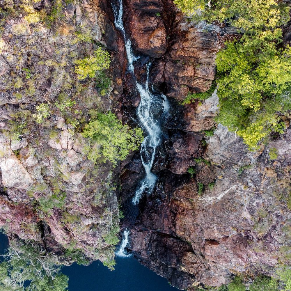 An overhead view of a water flowing onto a body of water. One of the many sites you see while on one of Litchfield National Parks best walks. This is Wangi Wangi Falls. 