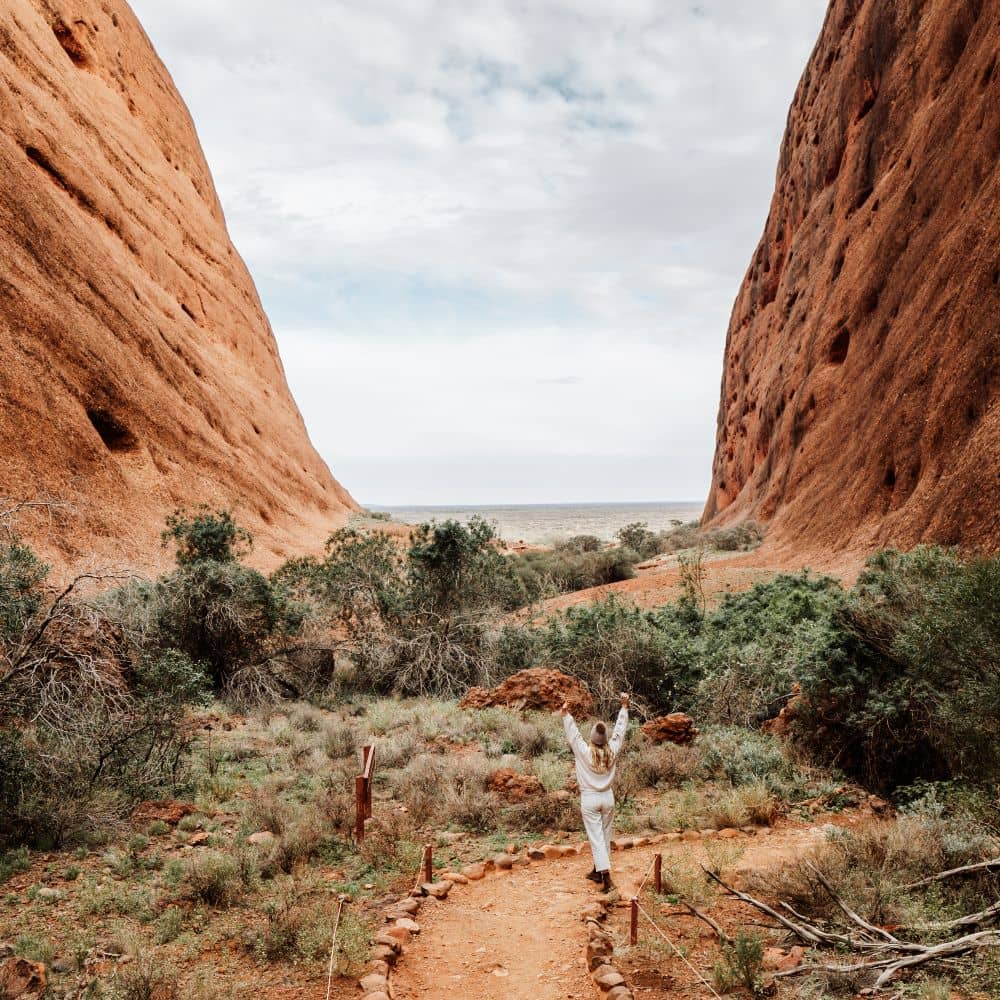 Woman with hands in the air looking at Uluru. This is clearly a good time to go to Uluru, according to the ultimate guide. This is located at Uluru in the NT.