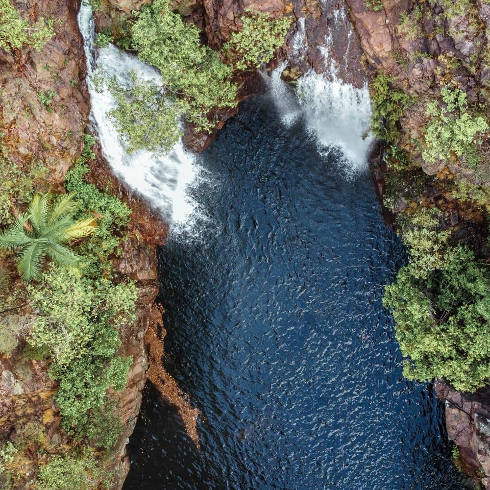 A waterfall pushing water into a body of water. One of the sites you can see doing the very best hiking available in the NT. Found in Litchfield National Park in Alice Springs, Northern Territory.