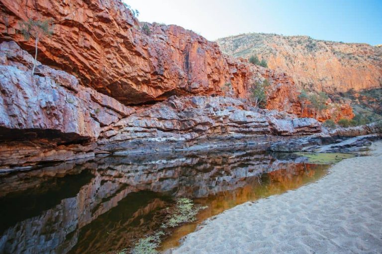 A rock formation with body of water underneath it. One of the best things to do in Alice Springs, Australia's red centre.