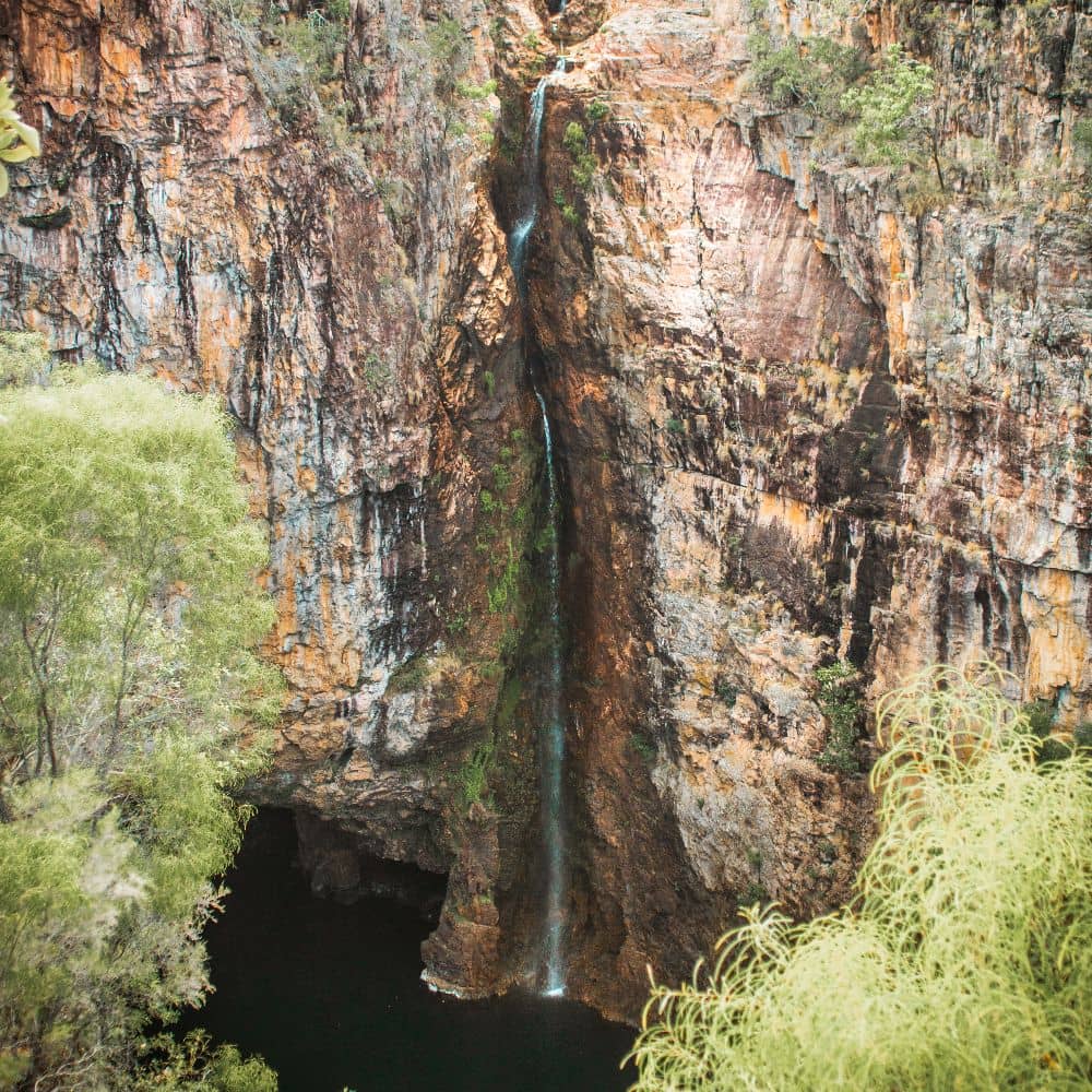 A tall but slender waterfall encased by a rocky mountain, displaying one of Litchfield National Park's seven best waterfalls, Tolmer Falls in the Northern Territory.