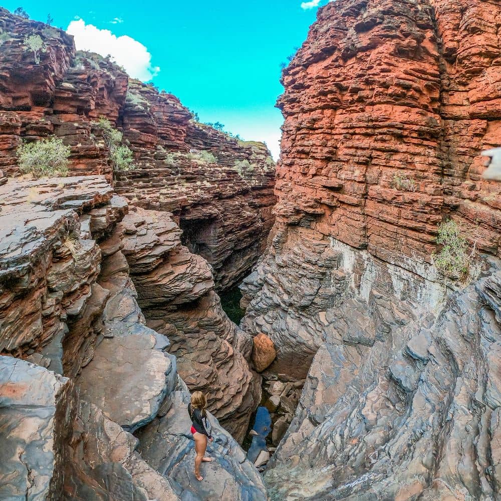 Women standing on rock formation overlooking water and rocks, as well as one of Joffre gorges pools in the middle of nowhere. This is in Joffre Gorge, Karijini.