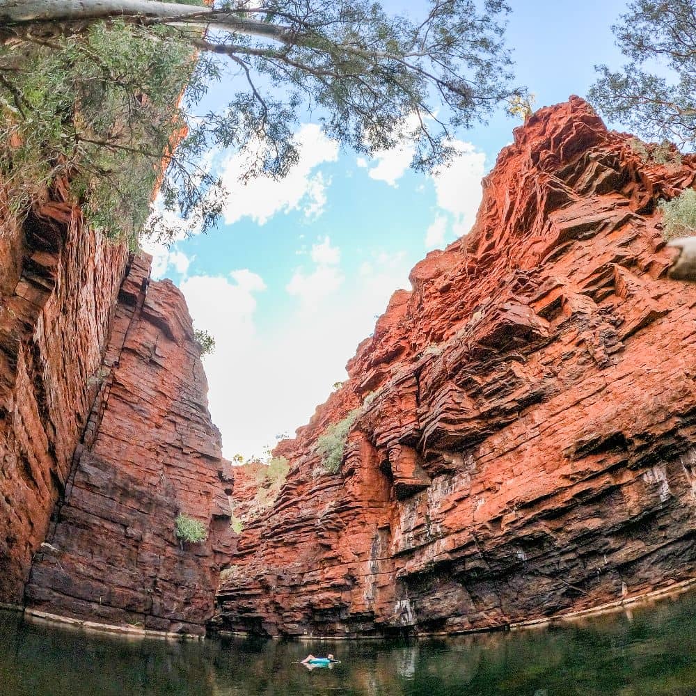 Women lying on inflatable ring while floating in the middle of a pool surrounded by a rock formation. Joffre gorge has an extensive range of things to offer, all in the middle of no where! This is the swimming hole at the Joffre Gorge in Karijini.