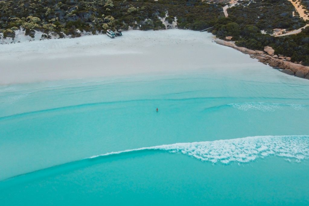 Woman standing on Twilight Beach in Esperance, Western Australia. Turquoise waters with waves crashing in front of her