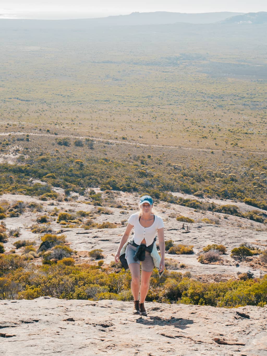 Woman hiking Frenchman Peak in Esperance, Western Australia. The background shows the landscape of Esperance