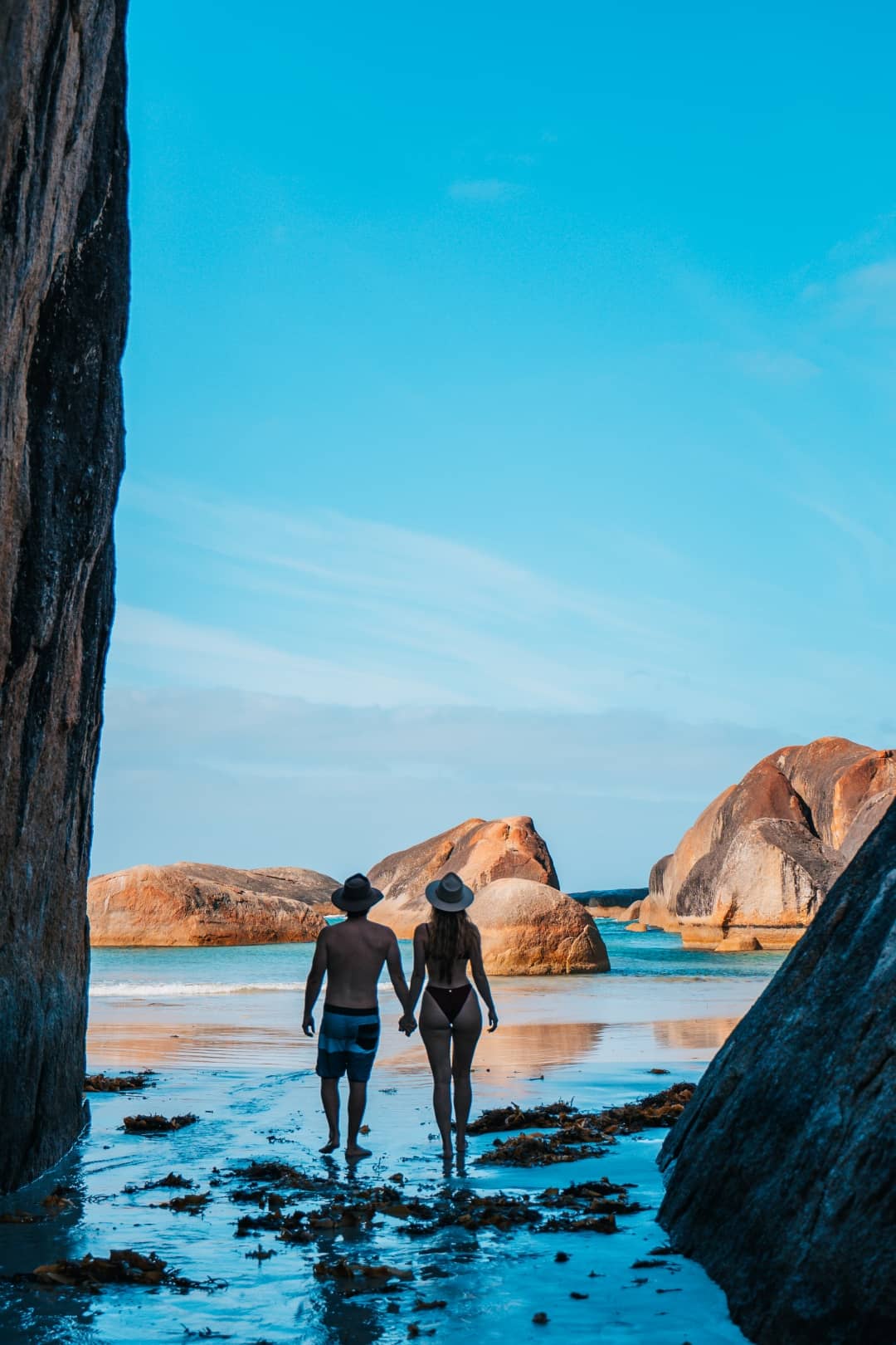 couple in their swimming attire holding hands while strolling at the beach in elephant rocks Denmark western australia