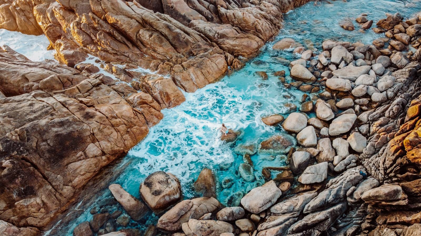 Aerial shot of Injidup Natural Spa in Yallingup, Western Australia, with waves flowing through rock formations into a tranquil natural pool