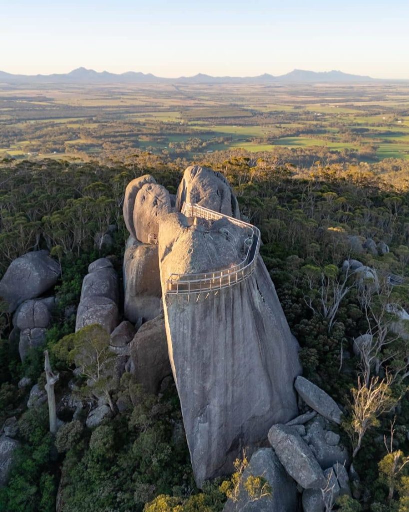 Granite Skywalk near Albany, Western Australia, built atop large rounded rock formations overlooking a vast forest and farmland landscape during a southwest road trip. The elevated walkway curves around the granite peak offering sweeping views across the valley below.