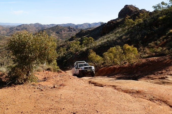 A 4WD vehicle ascending a steep, dusty trail on the Ridge Top, surrounded by the rugged landscape of Arkaroola Wilderness Sanctuary in South Australia.