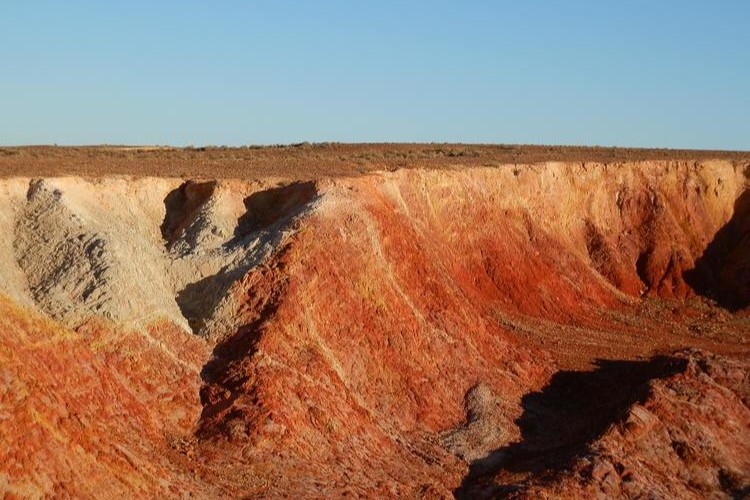 Colorful ochre pits at sunset in Copley, SA, showcasing vibrant red and orange sediment layers—a must-see among things to do in Copley, SA.
