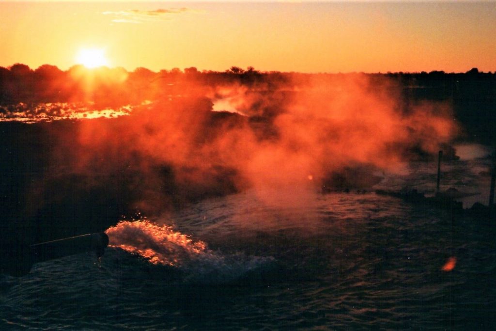 A vivid sunset at Thargomindah, Queensland, with steam rising from hot water in the foreground.