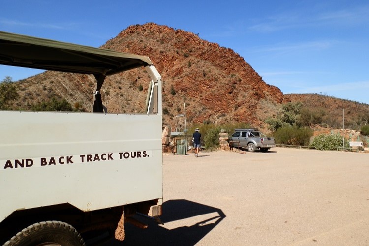 A Ridge Top Tour vehicle parked with a backdrop of red, rocky hills in Arkaroola—an adventurous activity among things to do in Copley, SA, offering scenic outback views.