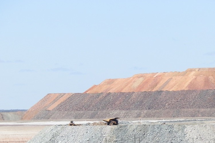 Mining trucks operate in the Super Pit Kalgoorlie, with layers of earth and rock visible in the background, reflecting the ongoing extraction activities.