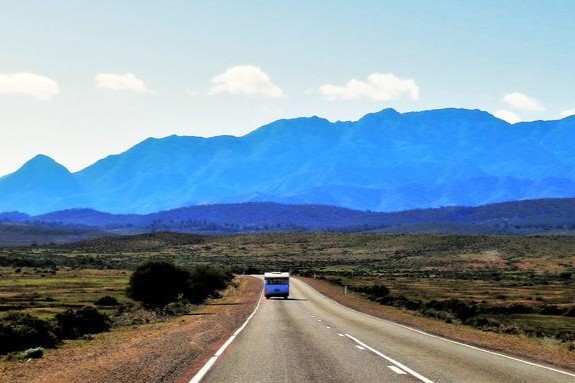 A scenic drive towards the Flinders Ranges, with the ranges' silhouette on the horizon in South Australia.