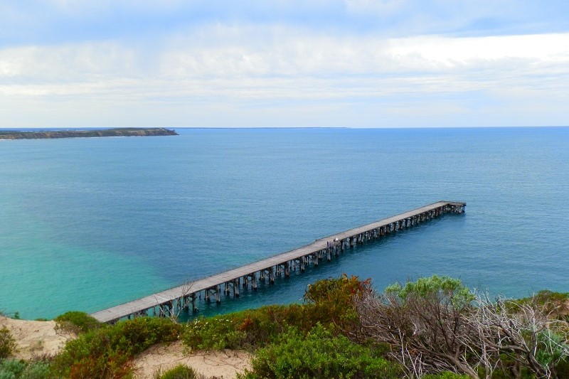 A view of the long wooden Stenhouse Bay Jetty extending into the clear turquoise waters at Dhilba Guuranda-Innes National Park, Yorke Peninsula, South Australia