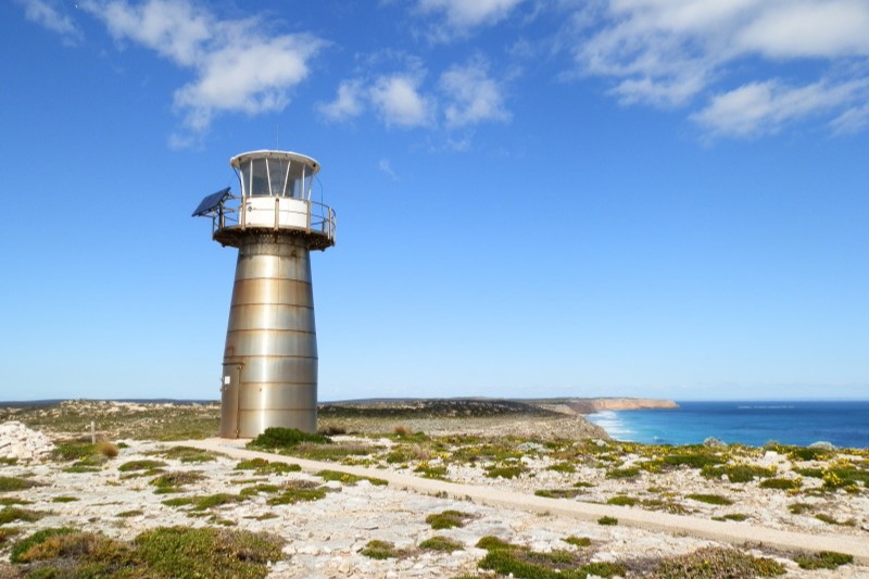 The modern metallic structure of West Cape Lighthouse stands against a blue sky and overlooks the ocean at Dhilba Guuranda-Innes National Park, Yorke Peninsula, South Australia.