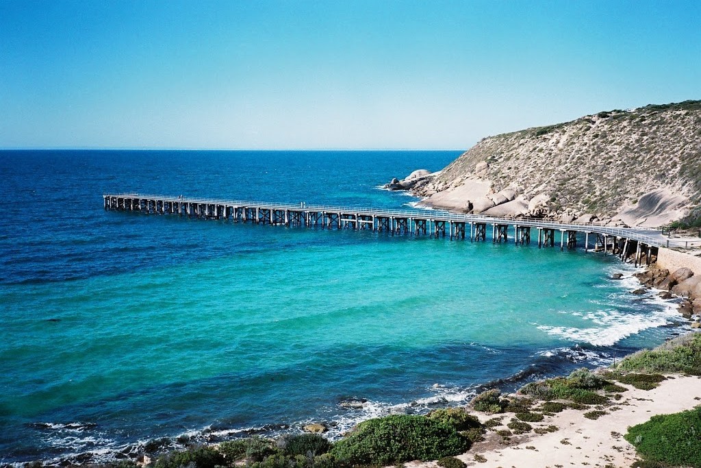 Stenhouse Bay Jetty extending into the turquoise waters at Dhilba Guuranda-Innes National Park, Yorke Peninsula, South Australia, with rocky cliffs in the background