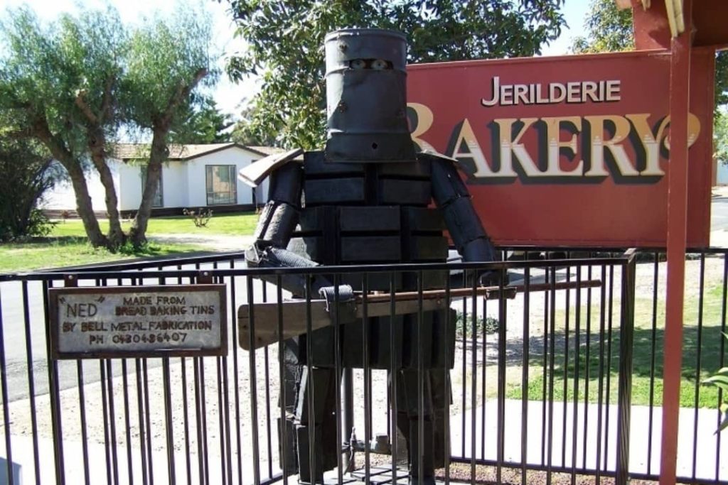 A metal sculpture of Ned Kelly, made from bread baking tins, stands in front of a bakery in Jerilderie, New South Wales.