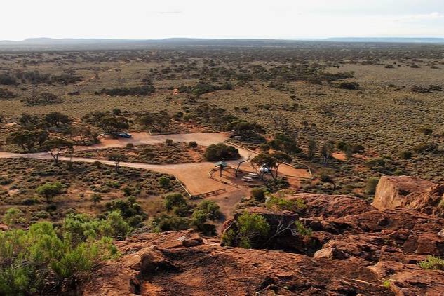 View of a small carpark area with a few scattered trees, seen from the top of Wild Dog Hill within Whyalla Conservation Park.