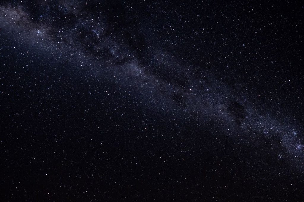 A stunning night sky over the Devils Marbles (Karlu Karlu) in the Northern Territory, Australia. The Milky Way stretches across the dark sky, with countless stars visible, creating a mesmerizing display of celestial beauty. The clear, unpolluted skies of the outback provide an ideal setting for stargazing and experiencing the vastness of the universe.