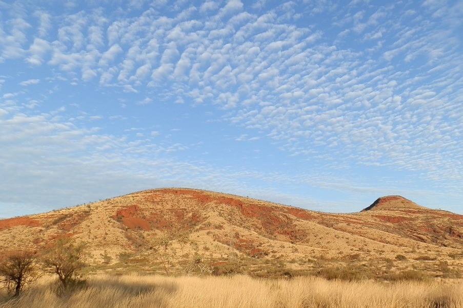 Expansive view of rolling hills under a cloud-dotted sky, a scenic stop for things to do in Tom Price.