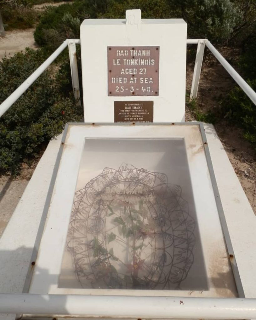 A memorial plaque dedicated to Dao Thanh Le Tonkinois, a 27-year-old who died at sea on 25 March 1940, located along the Stenhouse Bay Lookout Walk in South Australia. The grave site is marked by a wreath under a protective glass case, surrounded by native coastal shrubs.