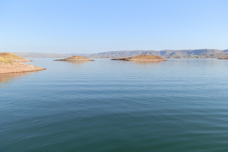 Small islands dotting the calm waters of Lake Argyle in Kununurra, surrounded by distant hills.