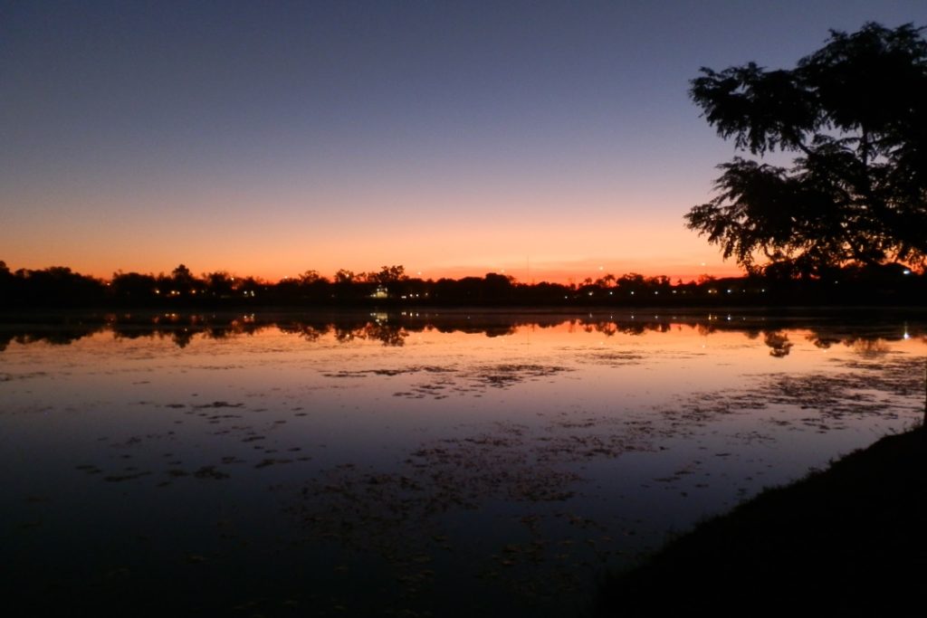 A serene sunset over the water in Kununurra, with the sky painted in shades of orange and purple.