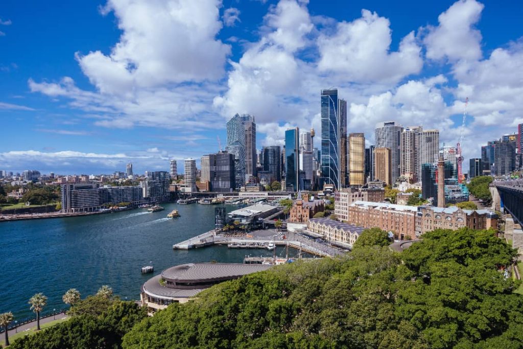 The stunning Sydney skyline is seen from the Harbour Bridge, with modern skyscrapers towering over the waterfront.
