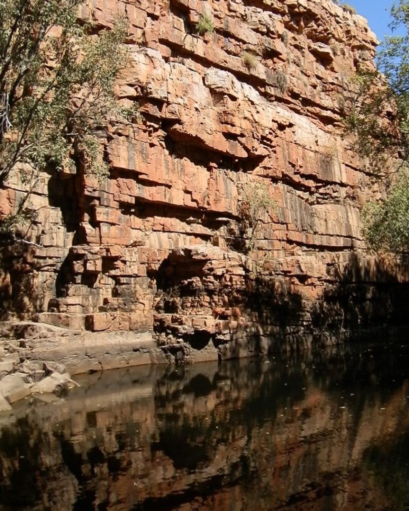 The Grotto cliff face near Wyndham, close to Kununurra, featuring rugged rock formations and a still water pool.