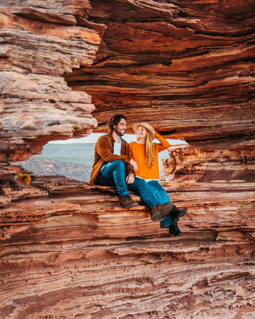A couple sitting within the iconic Nature’s Window rock formation overlooking the Kalbarri landscape.