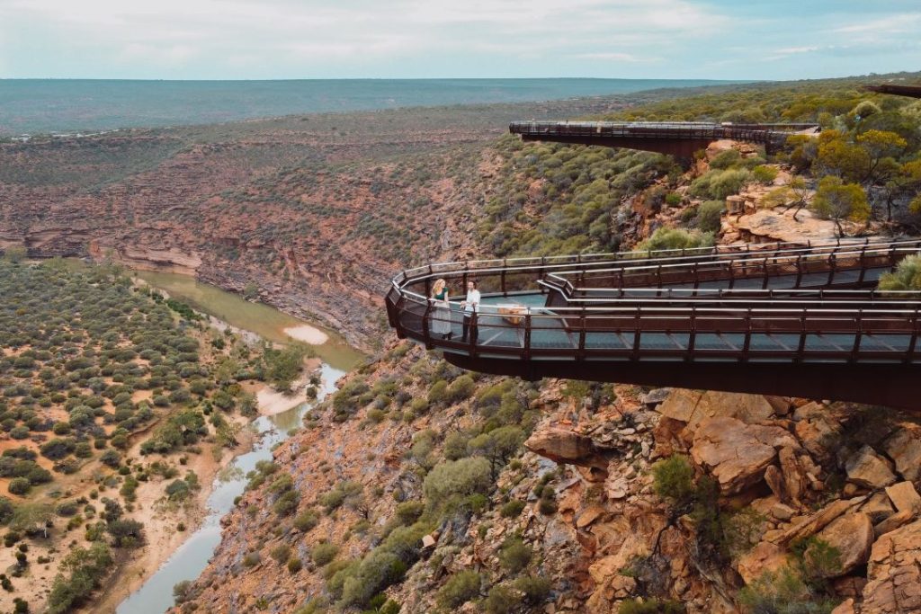wo visitors standing on the Kalbarri Skywalk, overlooking the dramatic Murchison Gorge and river below.