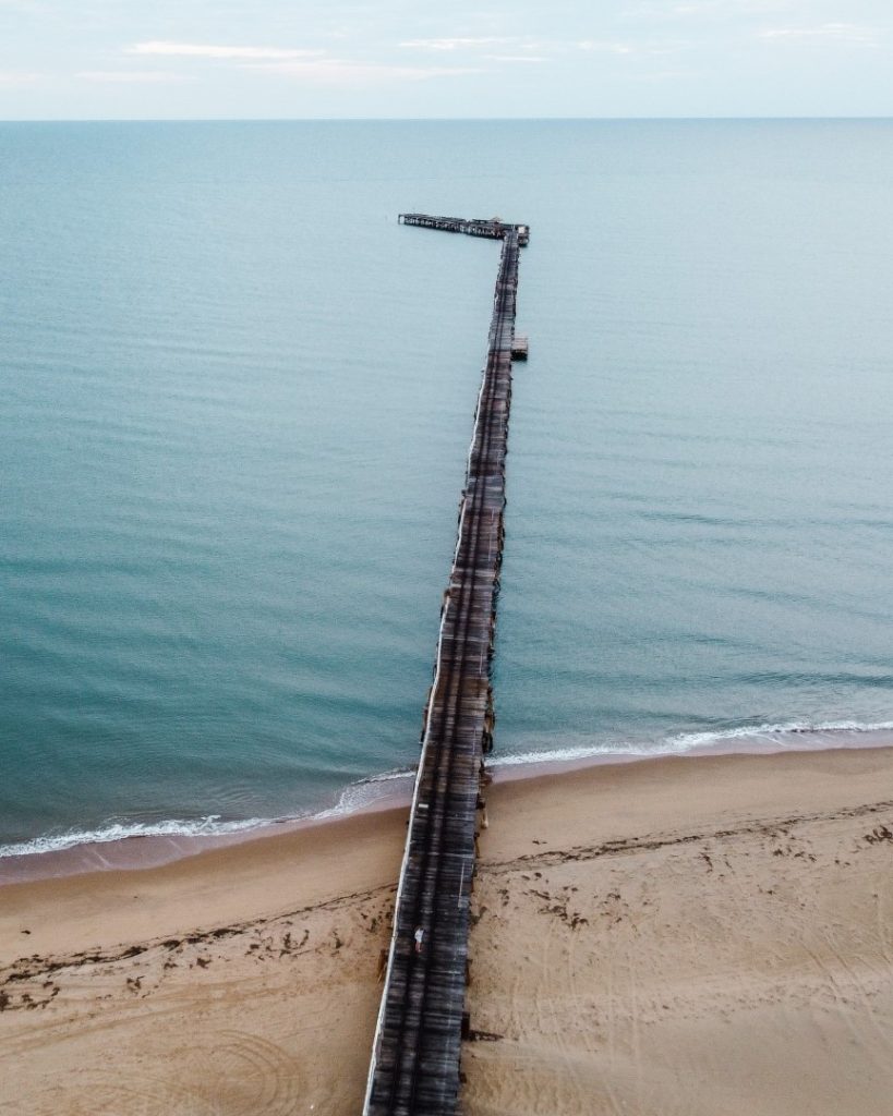 A long wooden wharf stretching out over calm, blue waters in Carnarvon