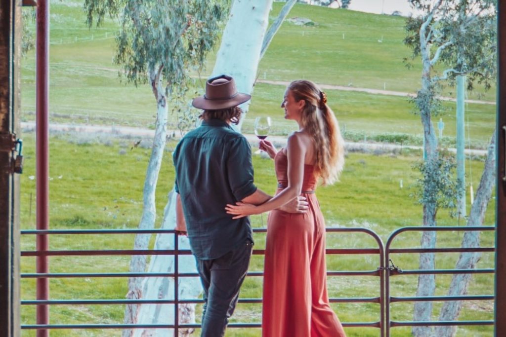 A couple enjoying wine while overlooking green vineyards at a Margaret River winery.
