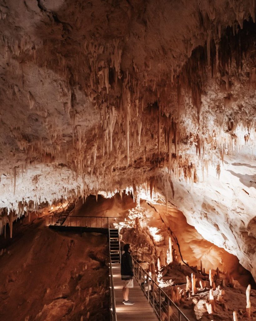 Visitor explores a cave filled with stalactites in Margaret River, Western Australia