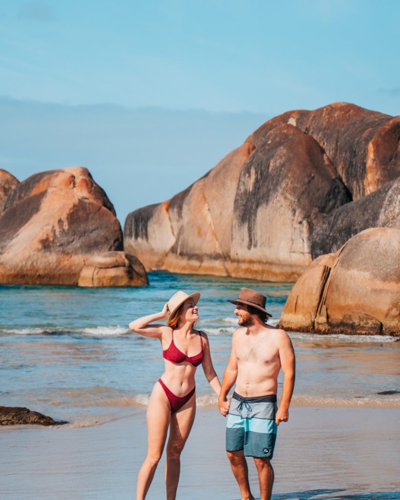 Couple walking along the beach near Elephant Rocks in Denmark, Western Australia.