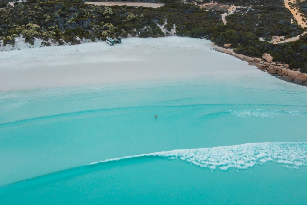 A pristine stretch of white sand and turquoise water at Twilight Beach in Esperance, Western Australia, with rolling waves and a rugged coastline