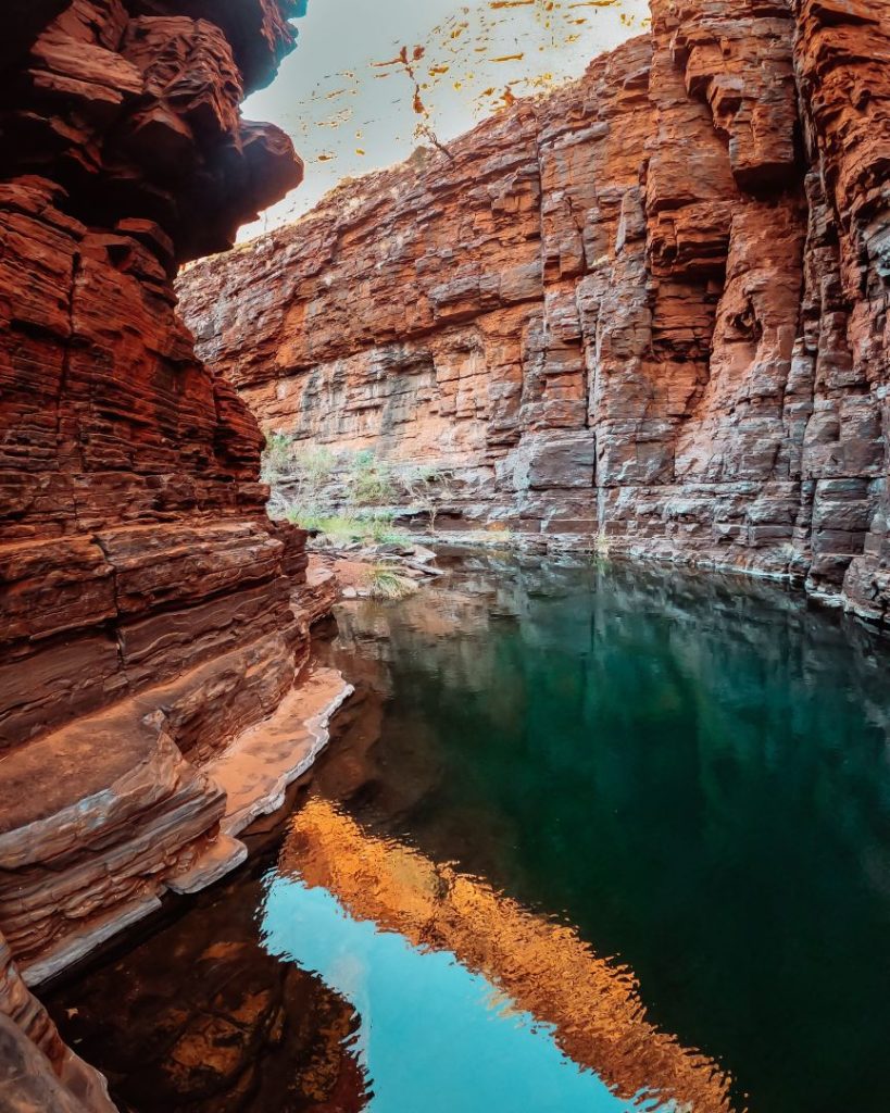 A tranquil pool of emerald water nestled between towering red rock walls in Joffre Gorge, Karijini National Park.