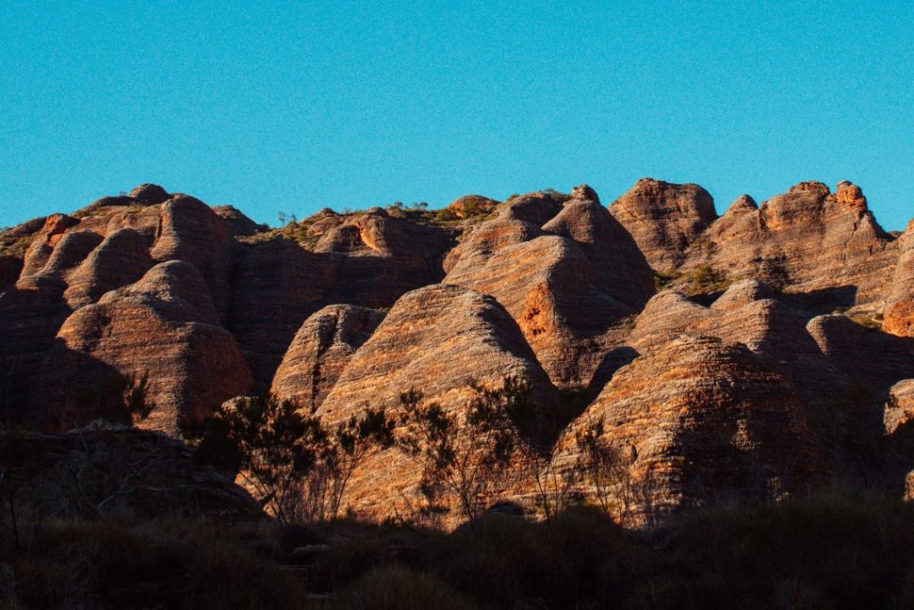 A panoramic view of the Bungle Bungles' unique, striped sandstone formations under a clear blue sky.