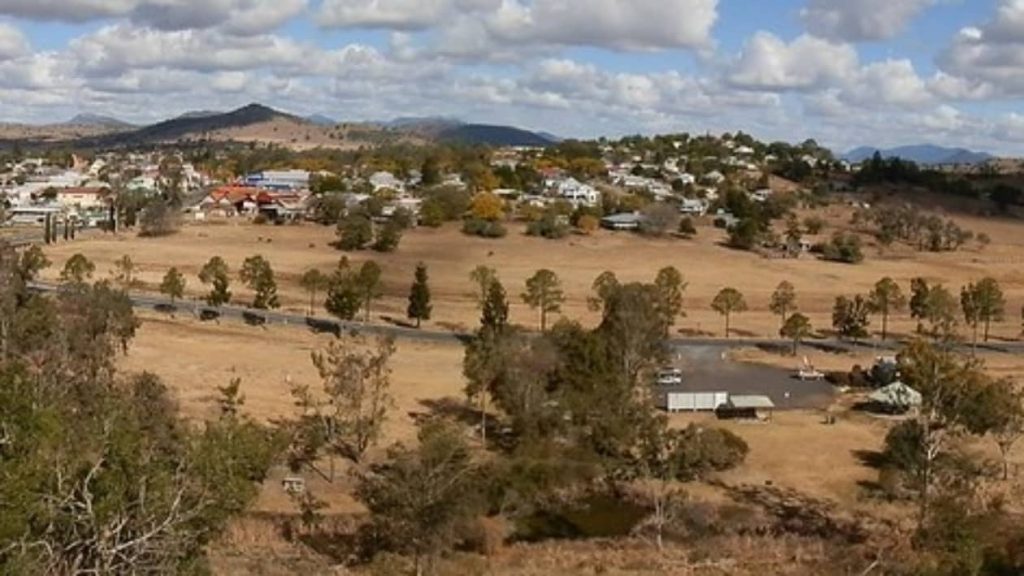 View over the town of Boonah from the lookout, showing the spread of buildings and dry fields surrounded by distant hills in the Scenic Rim, Queensland.