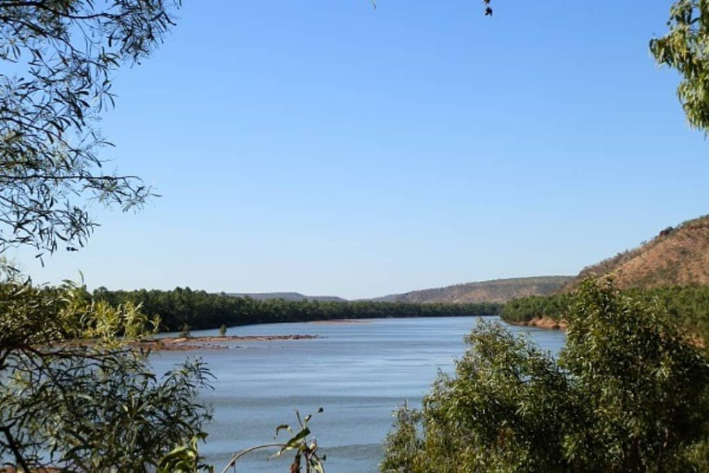 View from Policeman's Point Lookout overlooking the calm expanse of the Victoria River, framed by trees and distant hills in Timber Creek, Northern Territory.