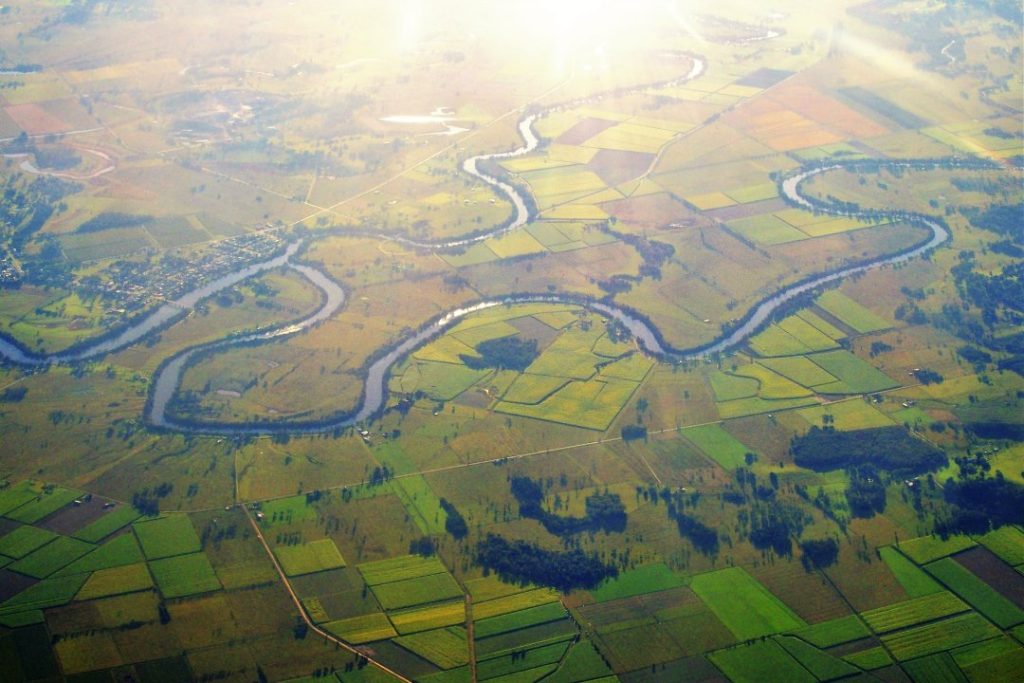 An aerial view of the Richmond River winding through lush farmland near Ballina, showcasing scenic river views as one of the tranquil things to do in Ballina NSW.