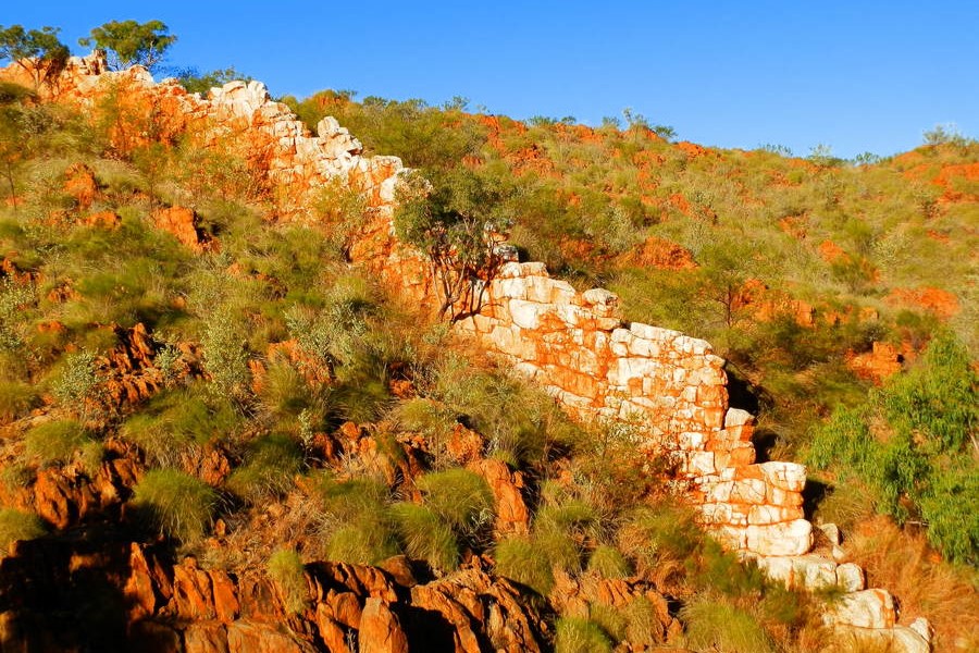 The natural quartz ridge known as the China Wall, stretching across red rocky terrain with sparse vegetation near Halls Creek.